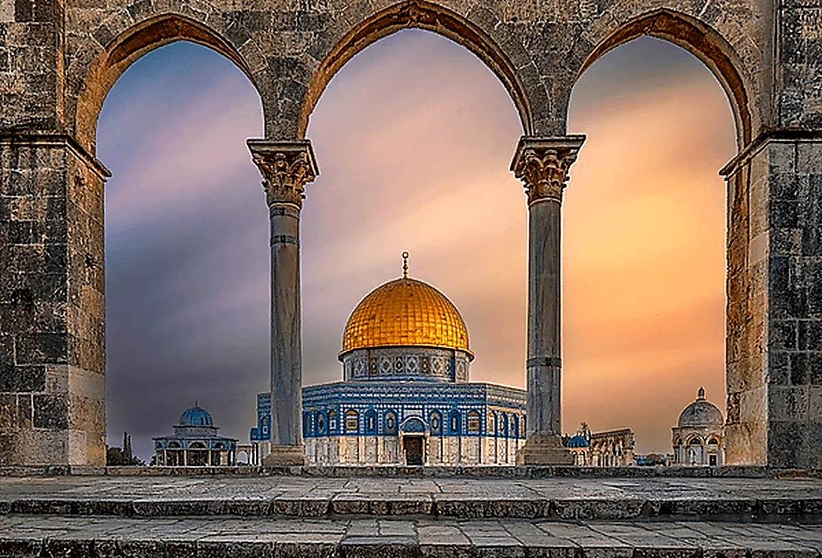 The Dome of the Rock seen through stone arches at dusk